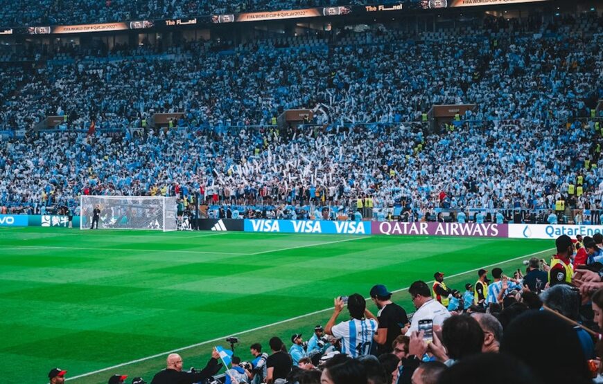 Fans fill a stadium during a FIFA World Cup match, with the field and packed stands visible ahead of the 2026 World Cup.