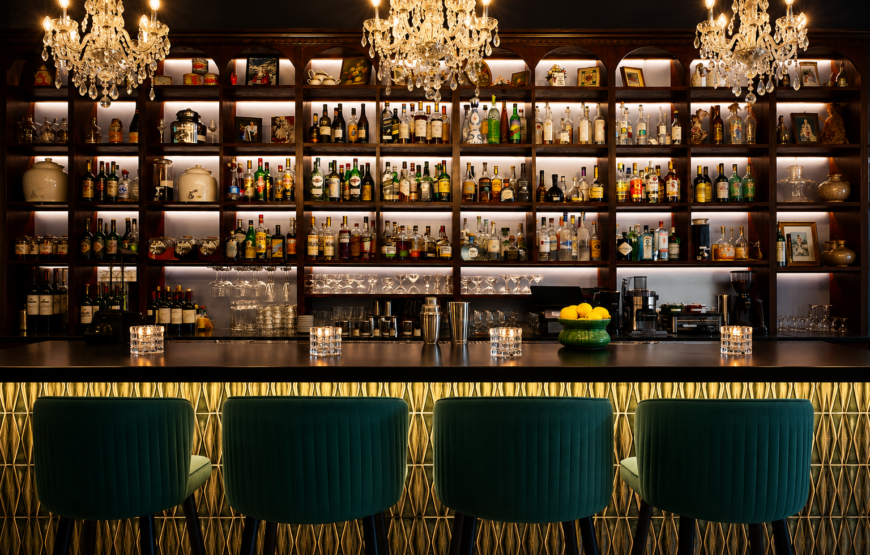 Upscale Montclair bar with liquor bottles displayed behind the counter, crystal chandeliers, and velvet seating.