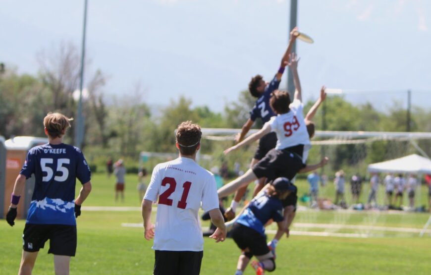 Montclair Ultimate Frisbee players compete for a disc during a youth Ultimate match on a grass field in New Jersey.