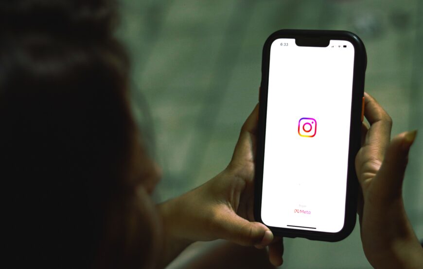 Person holding phone with Instagram app open, showing Meta branding, illustrating New Jersey's Meta settlement